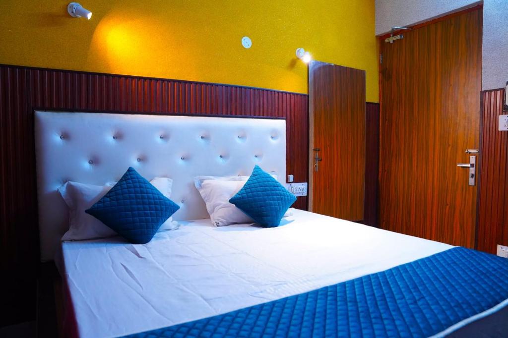 a bedroom with a large white bed with blue pillows at Hotel Apna Niwas in Una