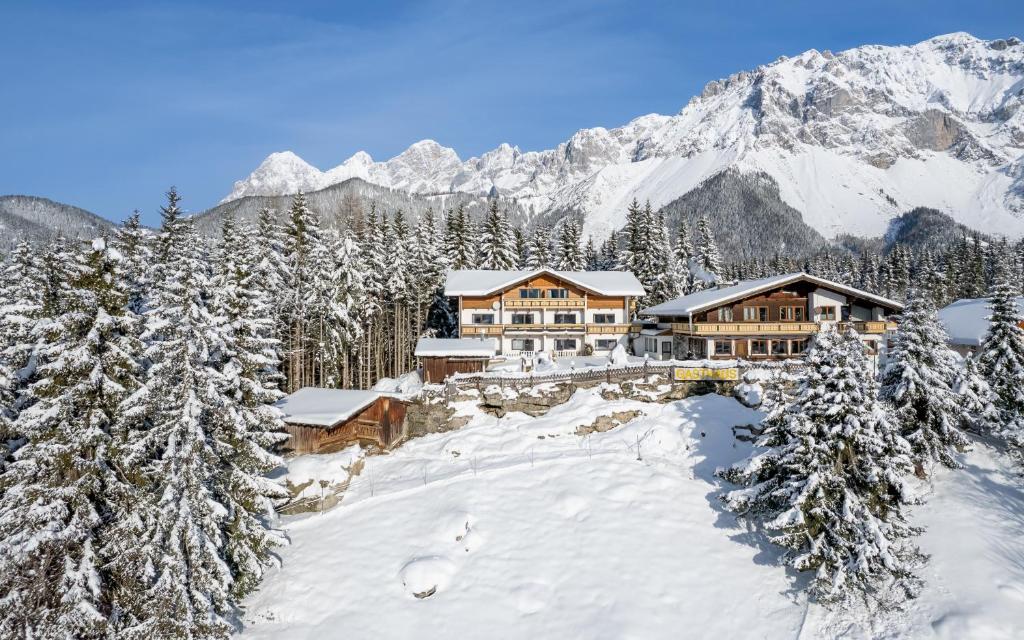 a lodge in the mountains with snow covered trees at Hotel Ramsaueralm in Ramsau am Dachstein