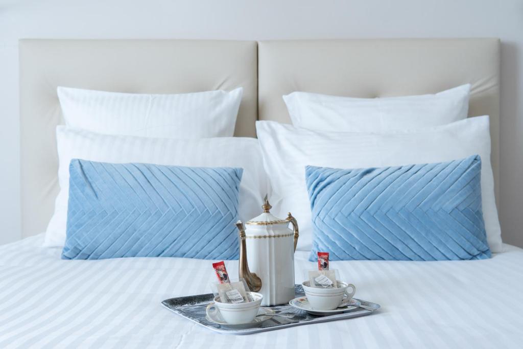ein Tablett mit zwei Tassen auf einem Bett mit Kissen in der Unterkunft Hôtel Le Grand Barnum in Francheville