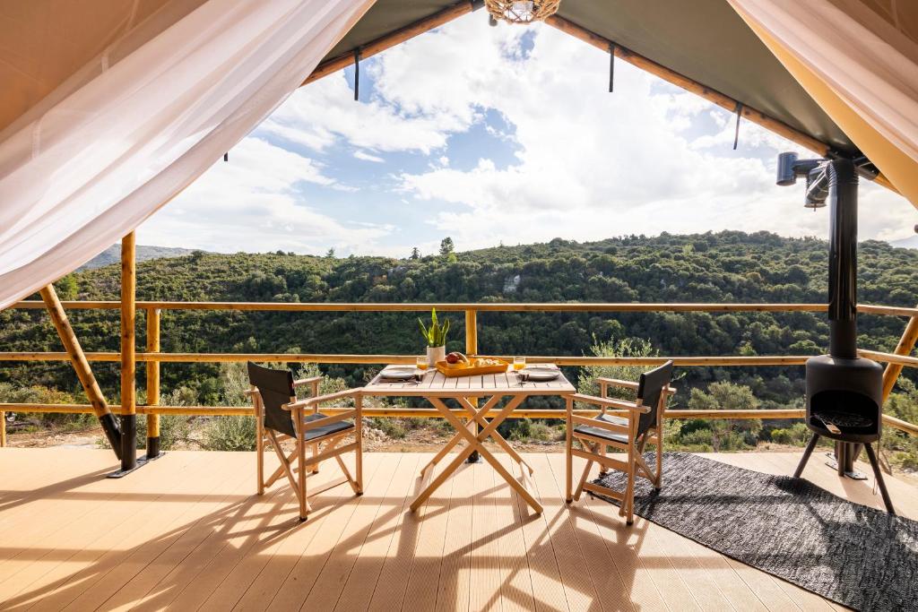 einen Tisch und Stühle auf einem Balkon mit Aussicht in der Unterkunft Civara Chalet - Private Glamping in nature with Jakuzzi in Tsivarás