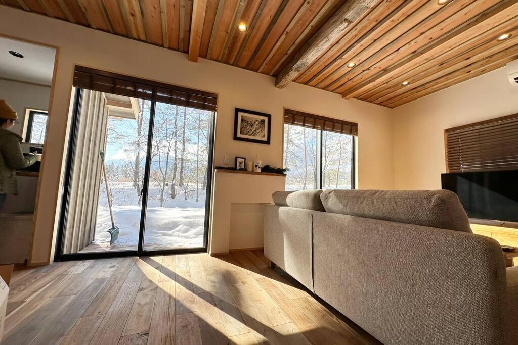 a living room with a couch and a sliding glass door at The Misorano Cottage in Hakuba