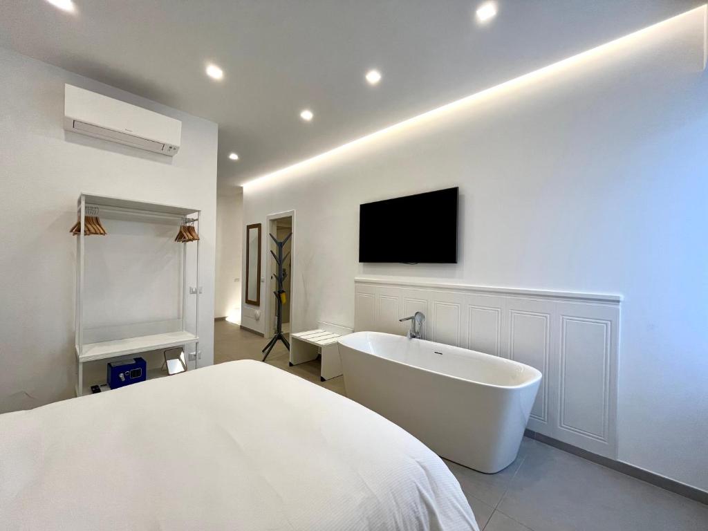 a white bedroom with a tub and a tv on the wall at TRASTEVERE URBAN SUITE in Rome