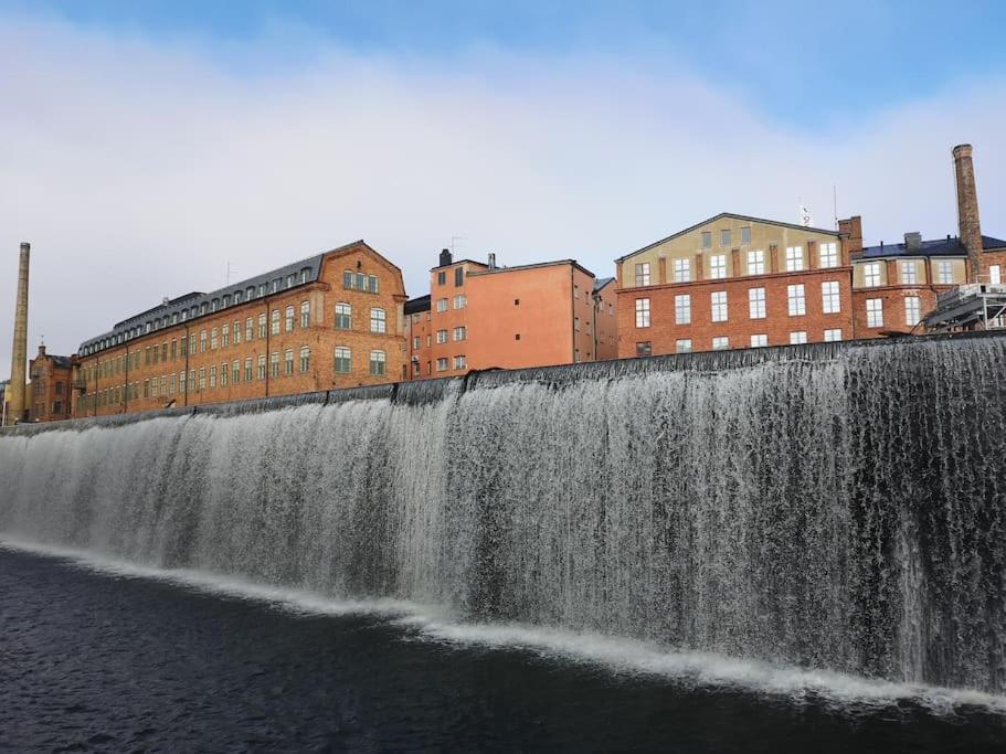 a waterfall on the side of a river with buildings at Stor lägenhet för familj eller företag in Norrköping