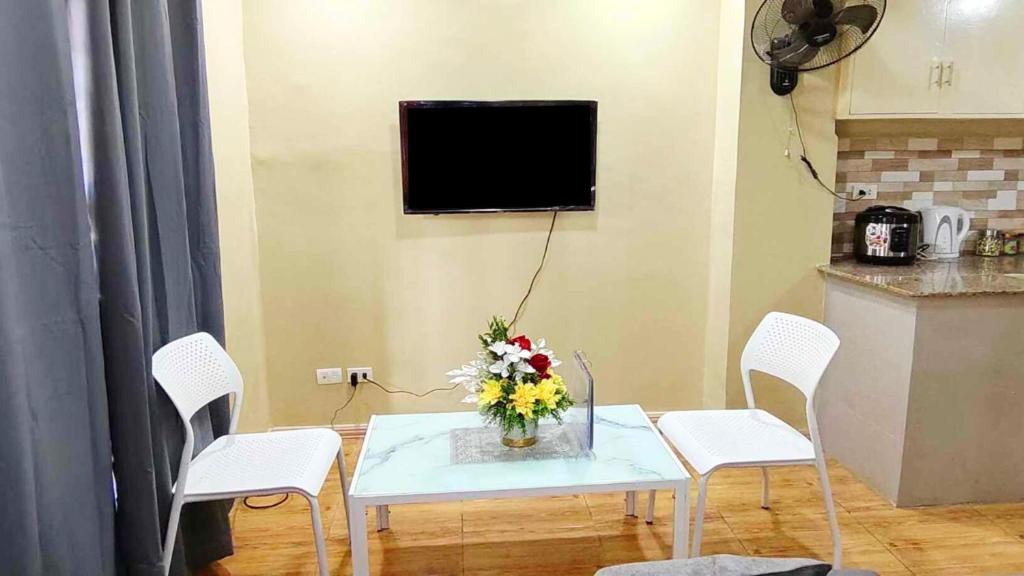 une table et des chaises avec un vase de fleurs. dans l'établissement Ormoc City Gate 2 Apartment, à Ormoc