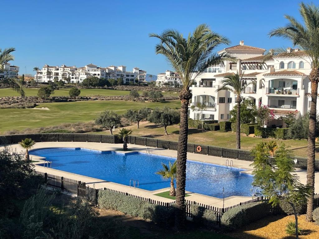 um resort com piscina e palmeiras em Apartment Lucy Hacienda Riquelme Golf resort em Múrcia