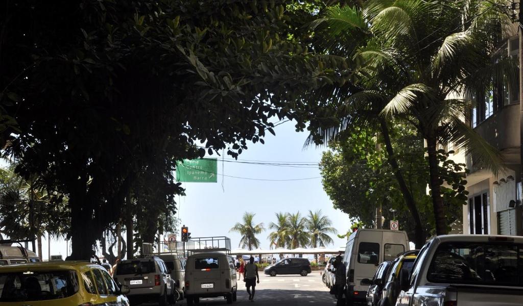 una calle con coches aparcados en una calle con palmeras en Studio Copacabana, en Río de Janeiro