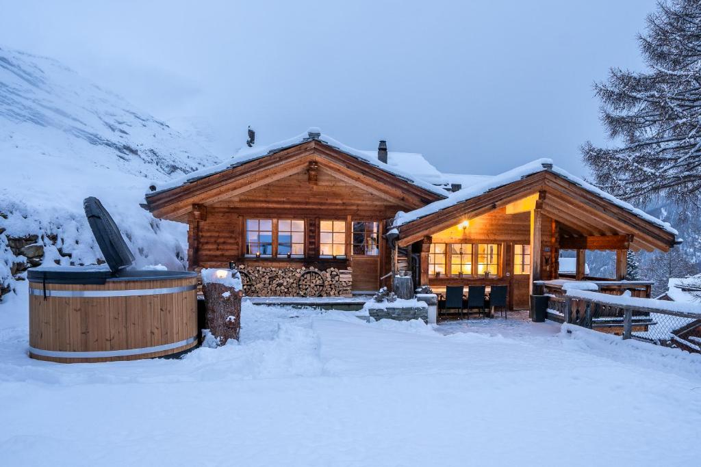 a log cabin in the snow with a hot tub at Ski in & out Chalet Marmo in Zermatt in Zermatt