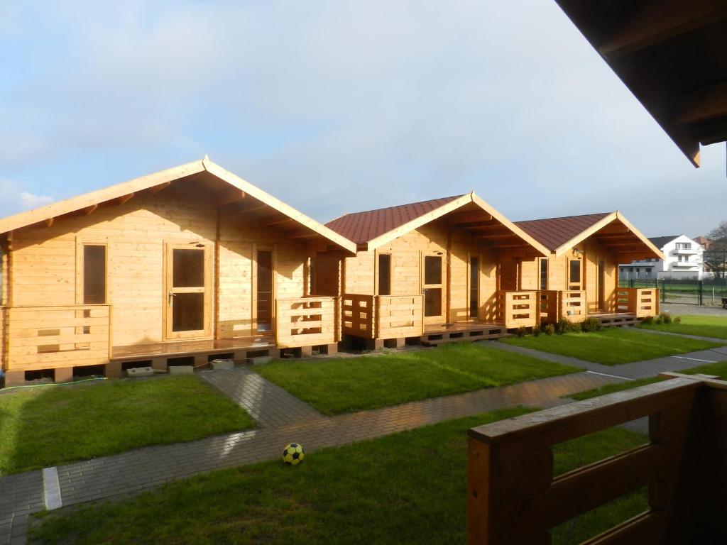 a row of wooden houses in a yard at Domki u Szostaków in Dąbki