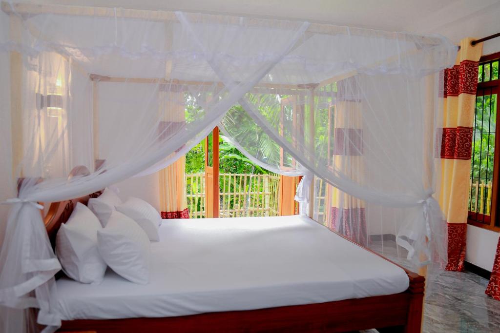 1 dormitorio con cama blanca con dosel y ventana en Sun See Villa Hikkaduwa en Hikkaduwa