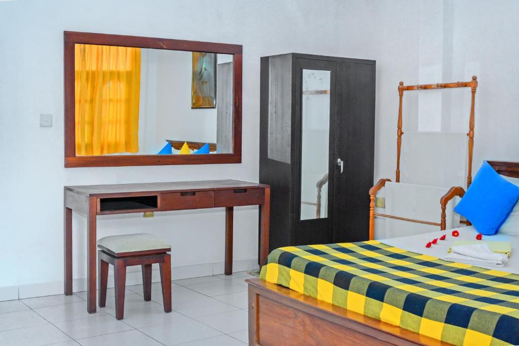 - une chambre avec un lit, un bureau et un miroir dans l'établissement SAKURAHANA VILLA AND AYURVEDA, à Aluthgama