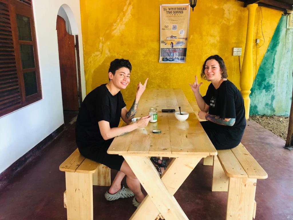 ウェリガマにあるWeligama Imal Guest Houseの木のテーブルに座る男女