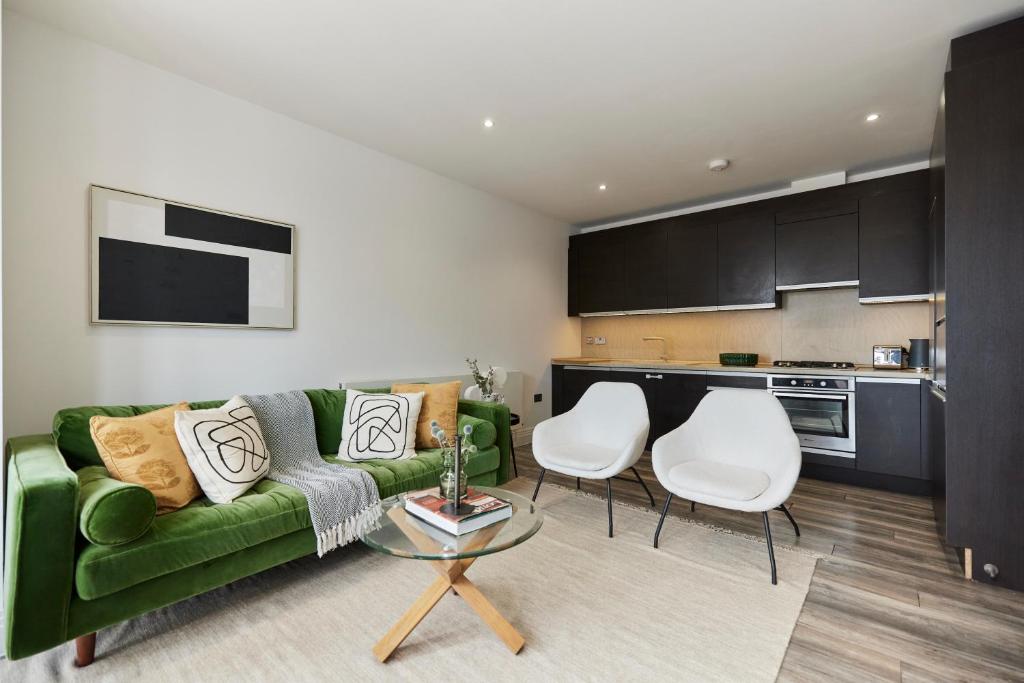 a living room with a green couch and two white chairs at The Wembley Hideaway - Bright 2BDR Flat in London
