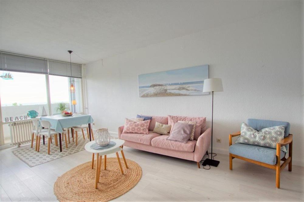 een woonkamer met een roze bank en een tafel bij Ferienpark - Haus L, App 0L0610 in Heiligenhafen