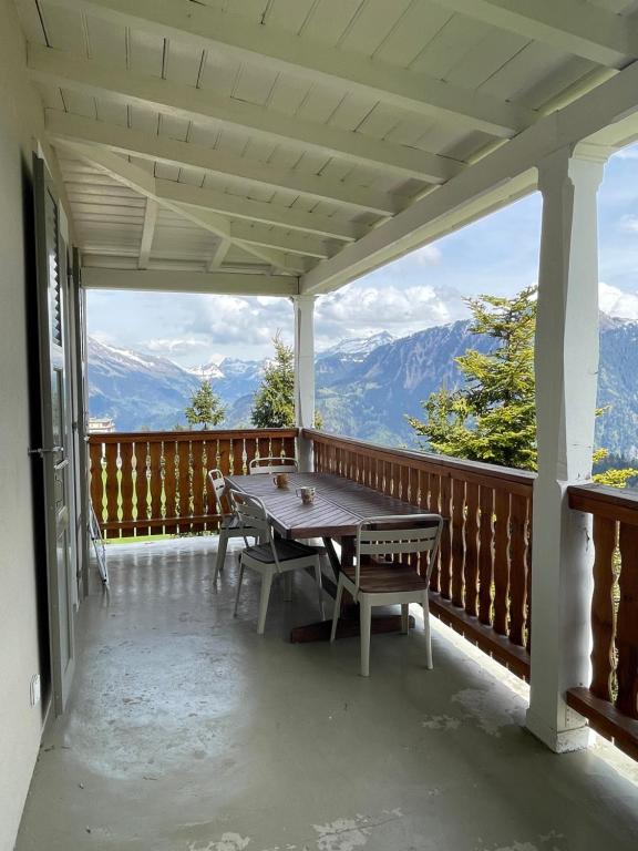 a wooden porch with a table and benches on it at Charmant appartement au Vagabond in Leysin