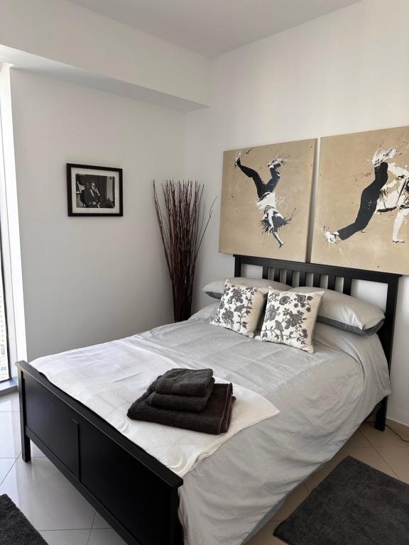 a bedroom with a large bed with two pictures on the wall at Amazing Double Room with En-suite, Marina and Sea views with shared kitchen in Dubai