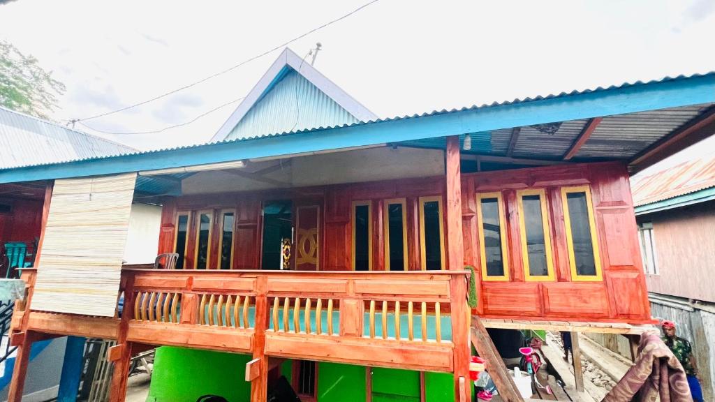 a house with a wooden porch with a blue roof at Jhuna Komodo Homestay in Komodo