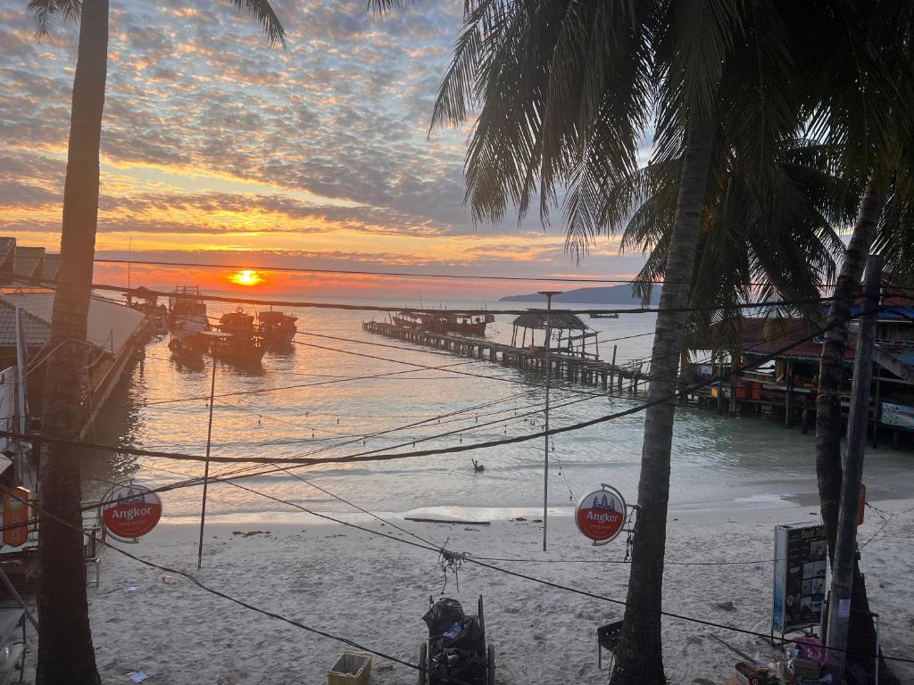 einen Sonnenuntergang über einem Strand mit einem Pier und dem Meer in der Unterkunft Family Guesthouse in Koh Rong