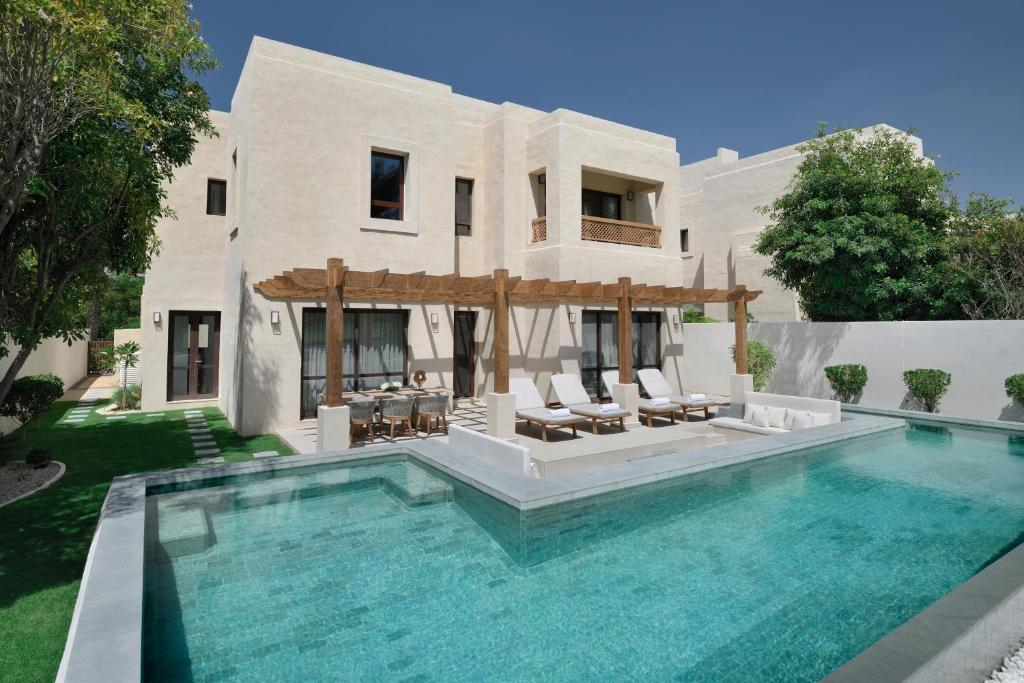 a house with a swimming pool in front of a house at Elara Villas in Dubai