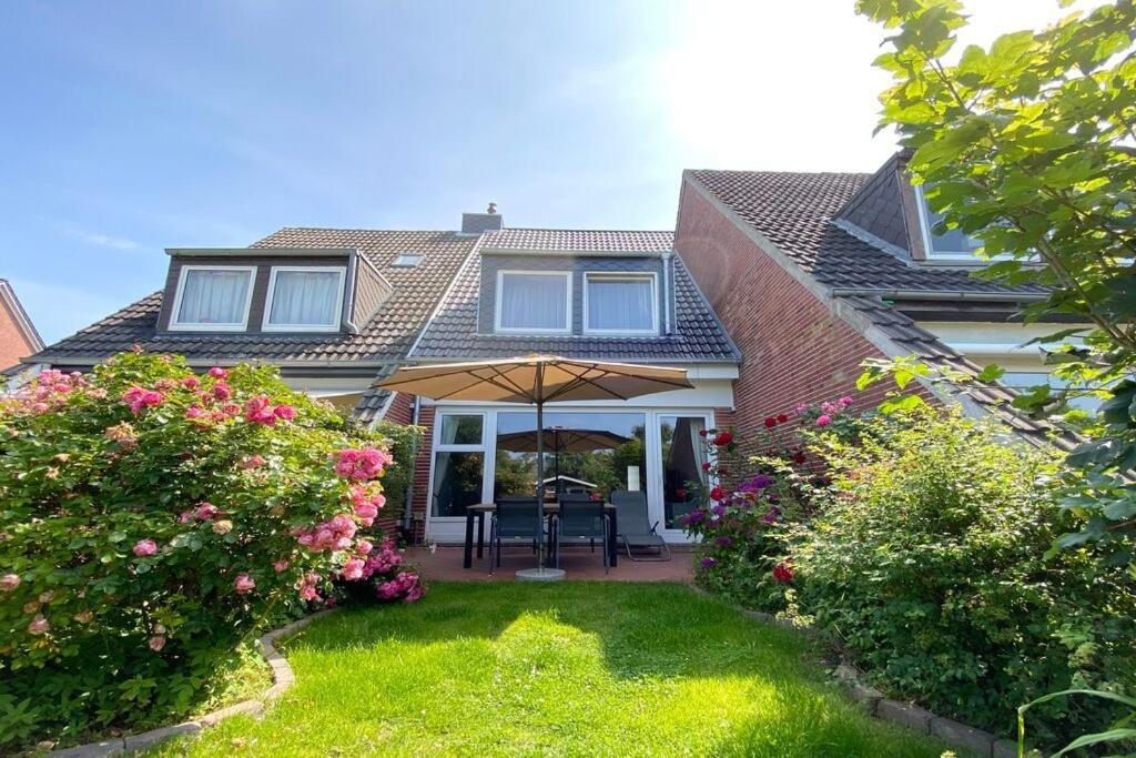 Cette maison dispose d'une terrasse avec un parasol. dans l'établissement Ferienhaus Barke 17, à Tinnum