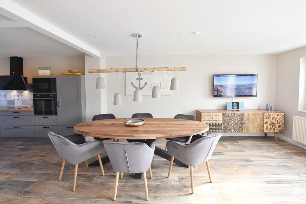une cuisine et une salle à manger avec une table et des chaises en bois dans l'établissement Ferienhaus Erika, à Tinnum