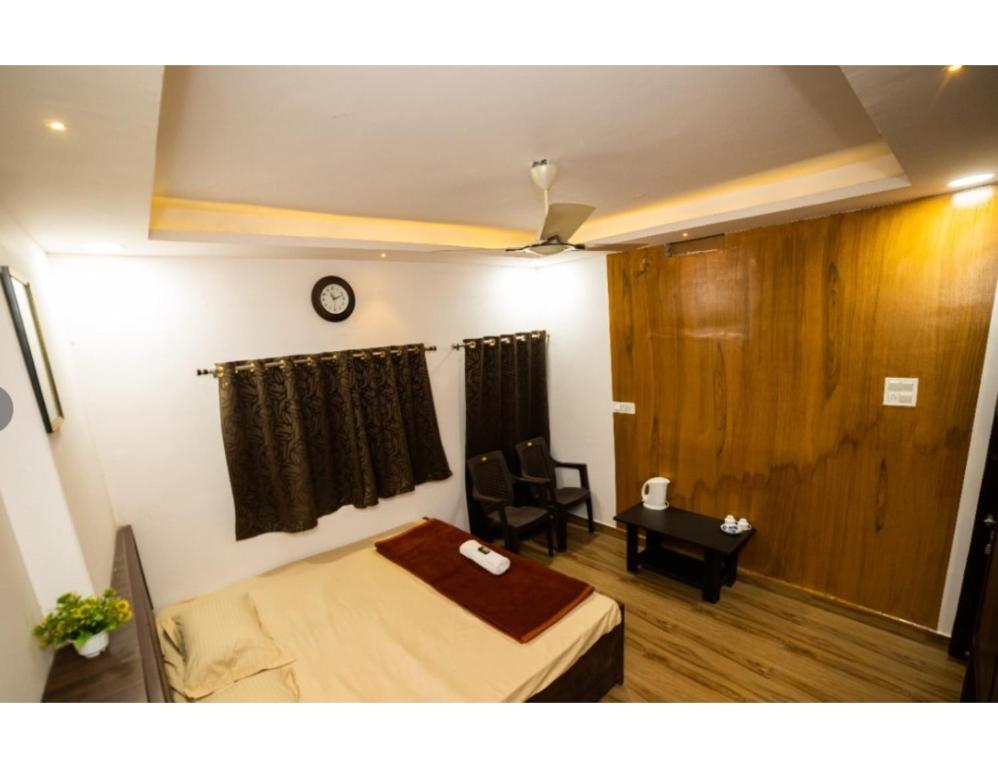 1 dormitorio con cama, mesa y reloj en Bisman Lodge, Jabalpur, en Jabalpur