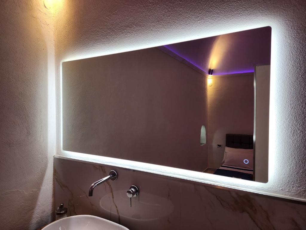 un bagno con un grande specchio sopra un lavandino di Anim Suite nel cuore di Ercolano a Ercolano