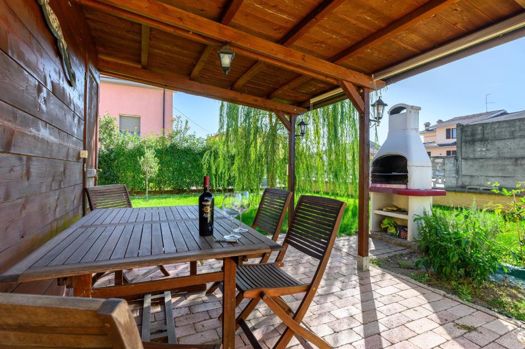 una mesa de madera y sillas en un patio con parrilla en Casa Vacanze Villa Lorella en Pontenure