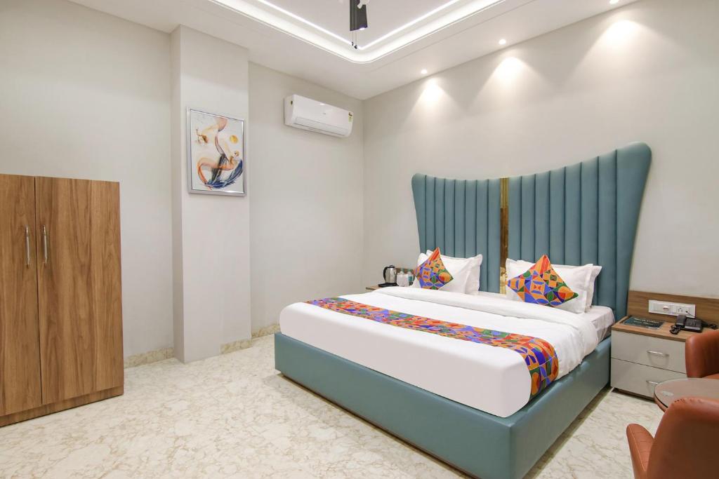 a bedroom with a large bed with a blue headboard at FabHotel Prime Royal Court in Ludhiana