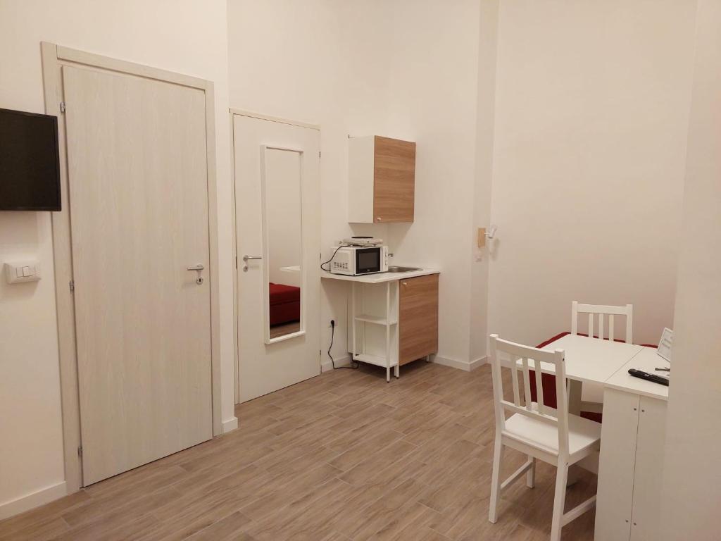 Kleines weißes Zimmer mit einem Schreibtisch und einer Mikrowelle. in der Unterkunft Residence e Appartamenti Ascensione in Neapel