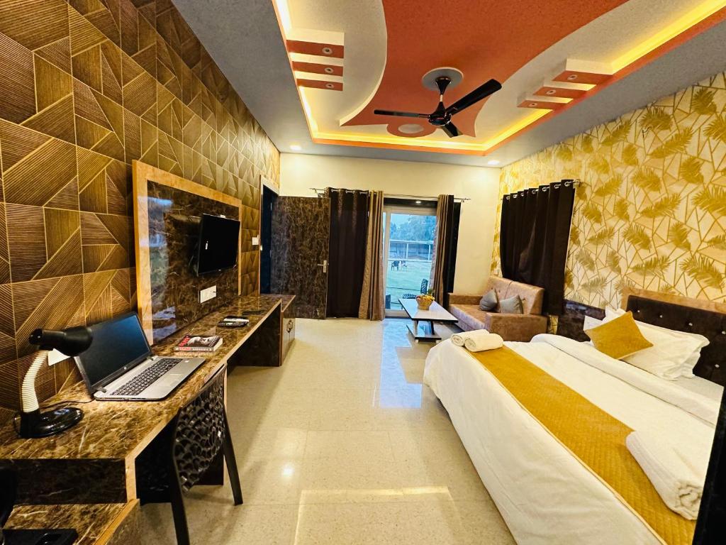 a hotel room with a bed and a desk with a laptop at Shree Yog Maya Resort in Pushkar