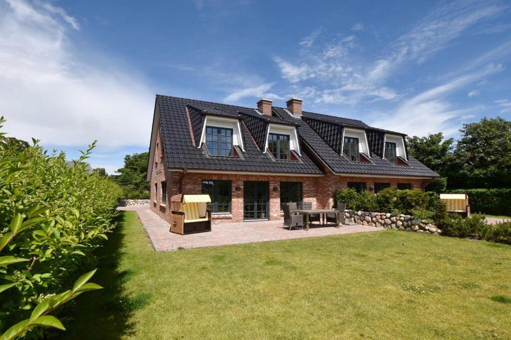 a large brick house with a roof on a lawn at Ferienhaus Hannah in Morsum