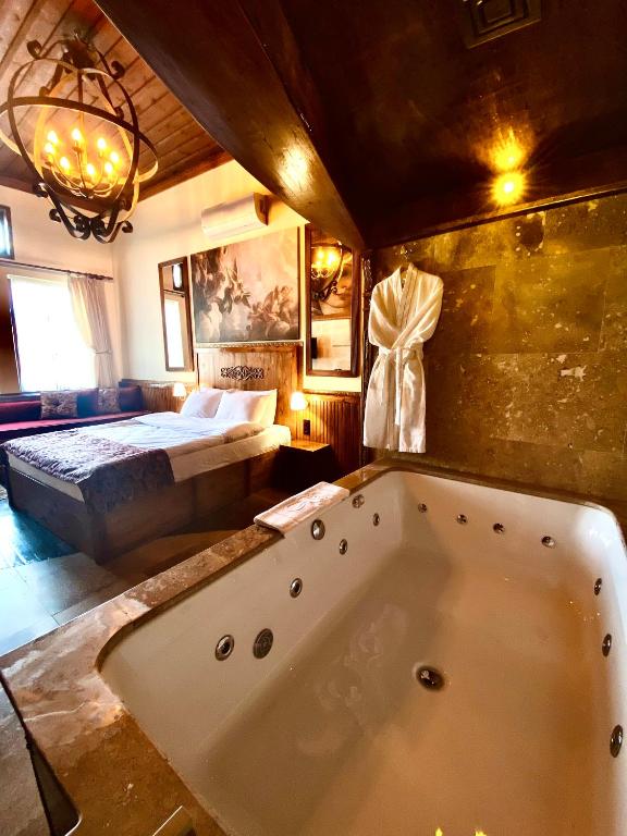 a large bath tub in a room with a bed at YOHANNES Stone Cappadocia in Ürgüp