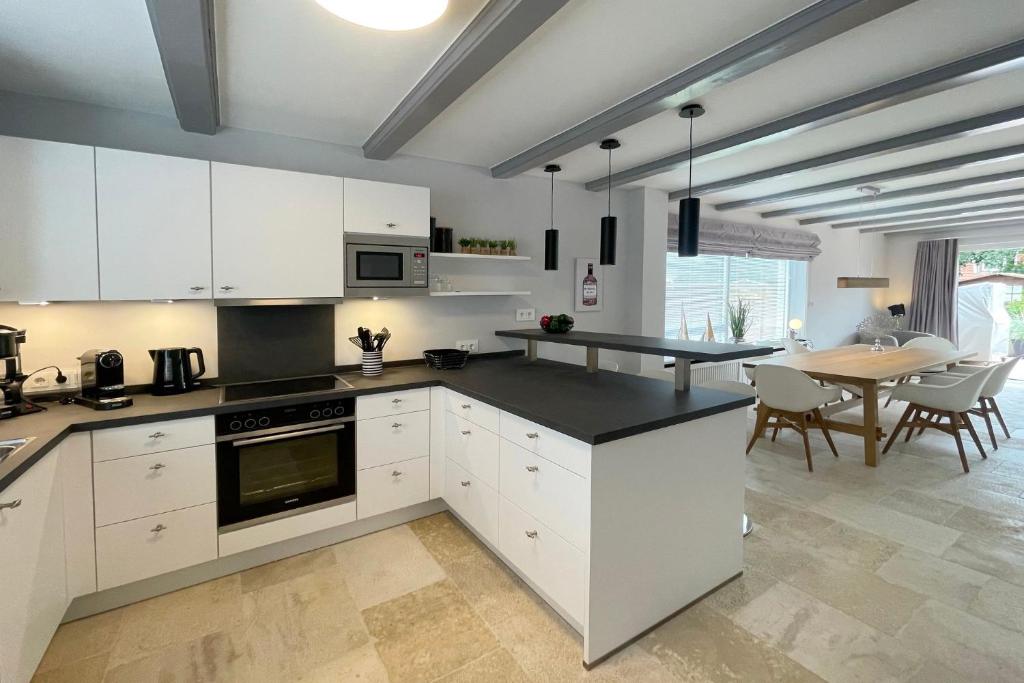 une cuisine avec des armoires blanches et une table avec des chaises dans l'établissement Ferienwohnung Goede Tiid, à Tinnum