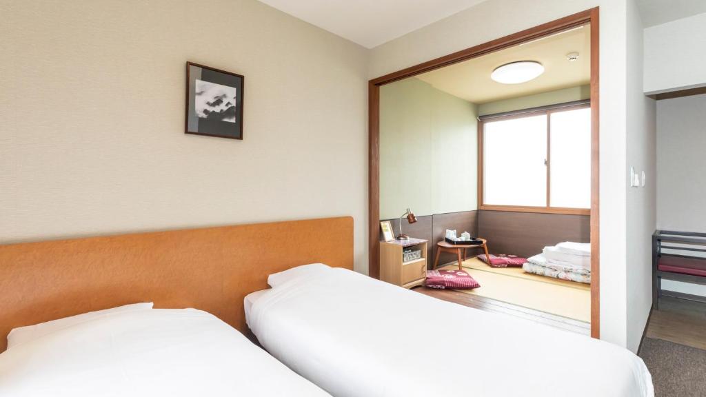 a bedroom with two beds and a mirror at Tabist International Hotel Kaike in Yonago