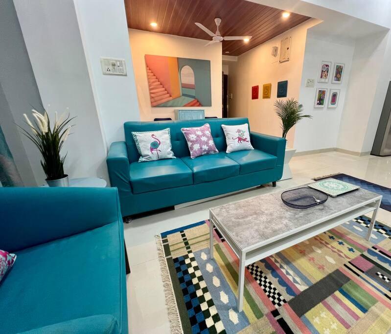 a living room with a blue couch and a table at Arc Nest, A Perfect Retreat in the Heart of Bandra by Connekt Homes in Mumbai