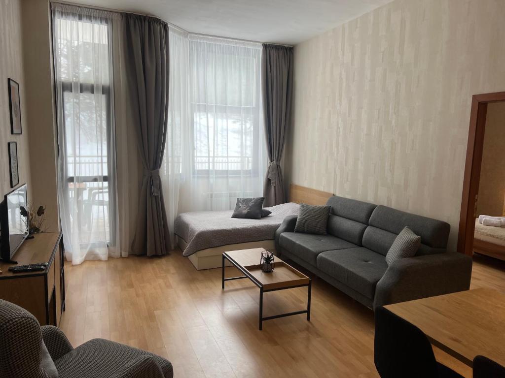 a living room with a couch and a coffee table at Flora Hotel Apartment 103 in Borovets
