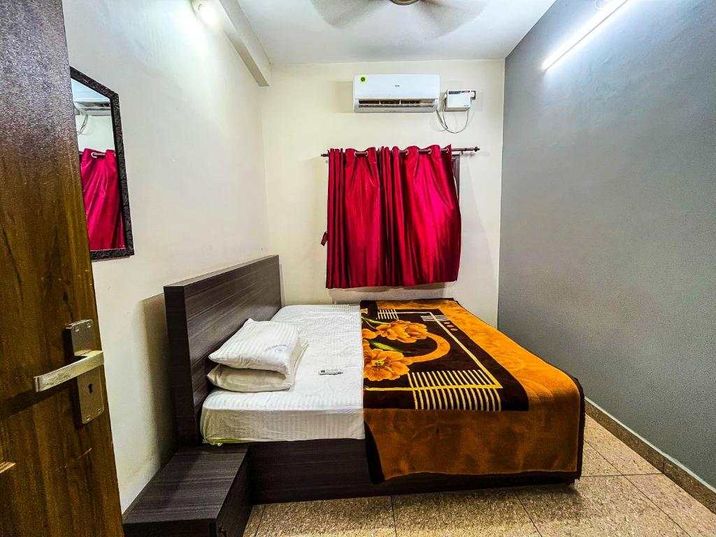 ein kleines Schlafzimmer mit einem Bett mit roten Vorhängen in der Unterkunft Royal Castle Residency in Puducherry