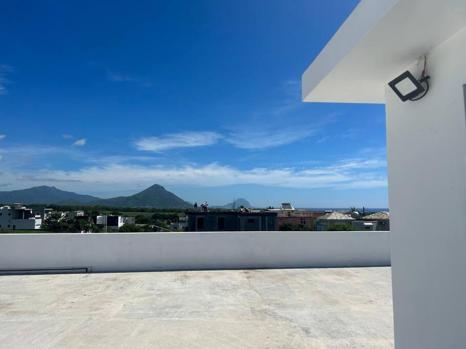 a view of the mountains from a white fence at Amazing Sunset view rooftop. in Flic-en-Flac