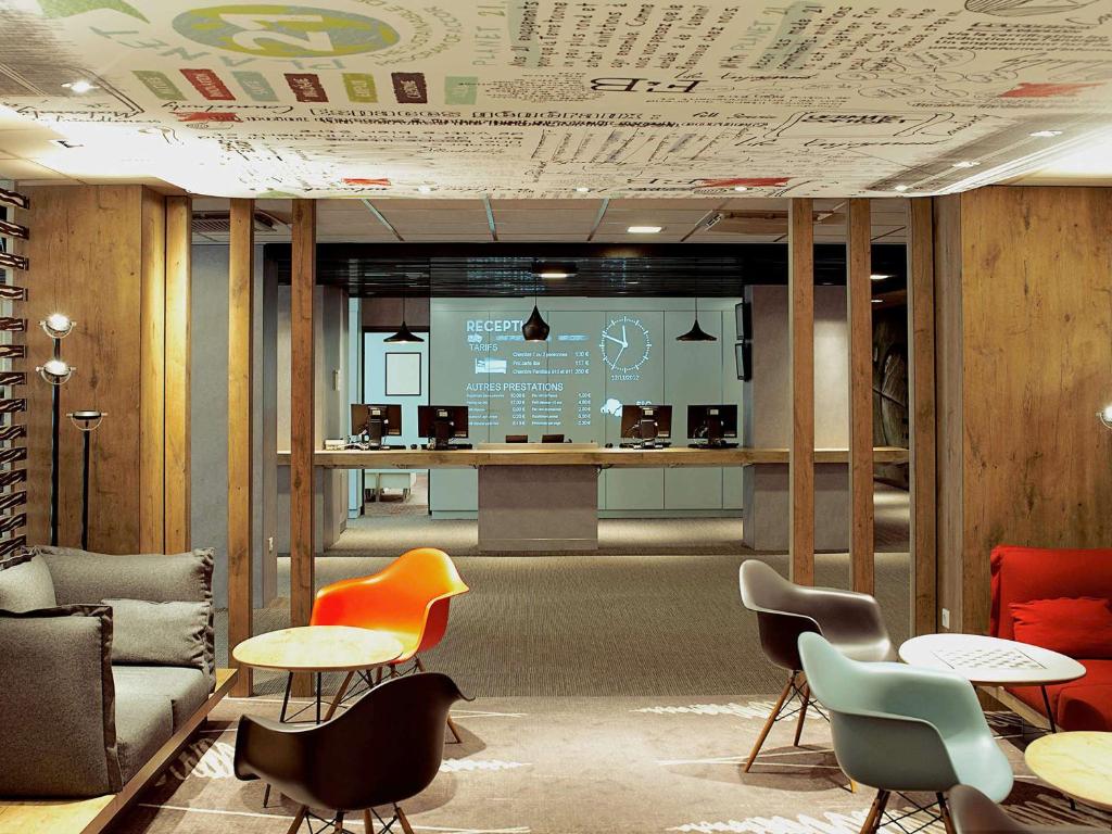 a lobby with chairs and tables and a screen at ibis Paris Porte D'Orleans in Montrouge