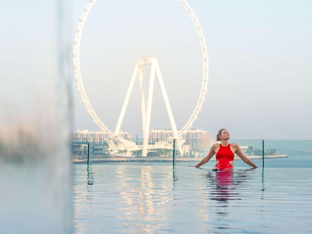 een vrouw in het water voor het Londonoog bij Sofitel Dubai Jumeirah Beach in Dubai