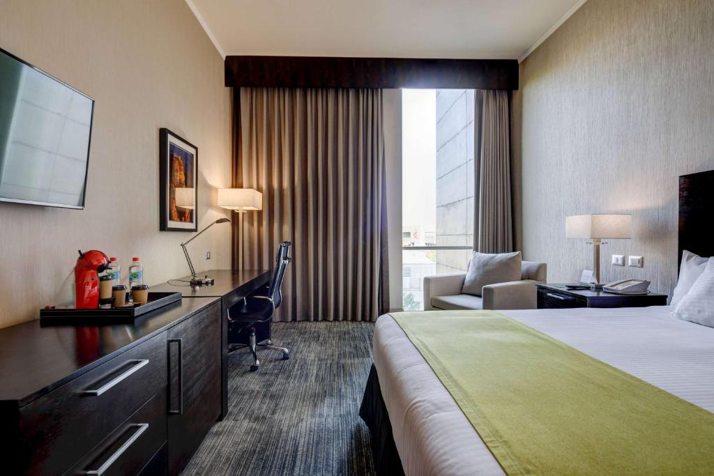 a hotel room with a bed and a desk at La Quinta by Wyndham Santiago Aeropuerto in Santiago