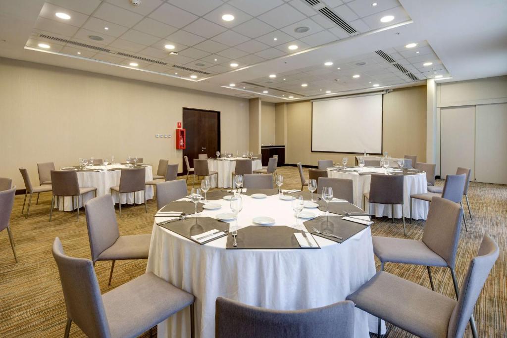 a conference room with tables and chairs and a screen at La Quinta by Wyndham Santiago Aeropuerto in Santiago
