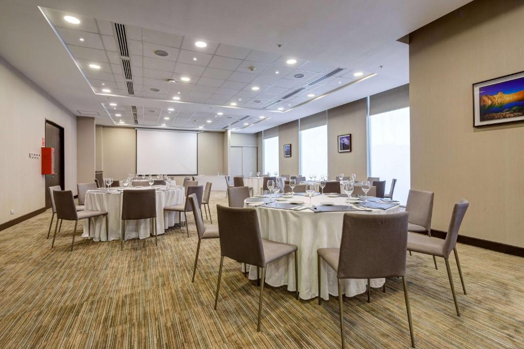 a conference room with tables and chairs and a screen at La Quinta by Wyndham Santiago Aeropuerto in Santiago