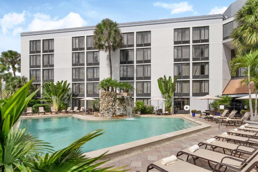 an exterior view of a hotel with a pool and lounge chairs at Doubletree by Hilton Fort Myers at Bell Tower Shops in Fort Myers