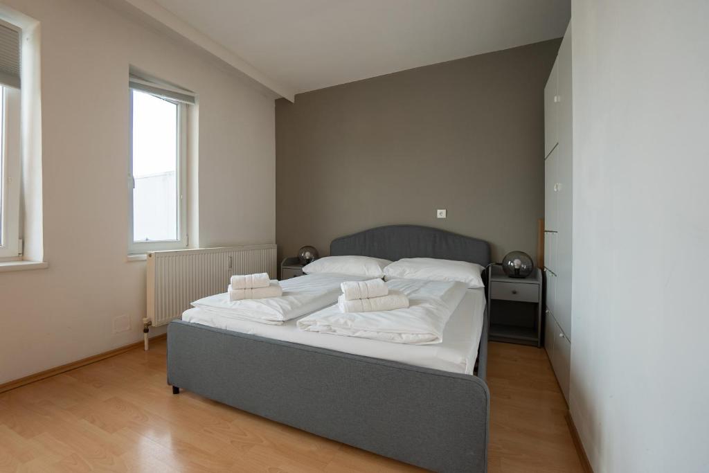 1 dormitorio con 1 cama con sábanas y almohadas blancas en Apartment with a private terrace located right near Belvedere Castle, 15 minutes away from Stephansdom, en Viena