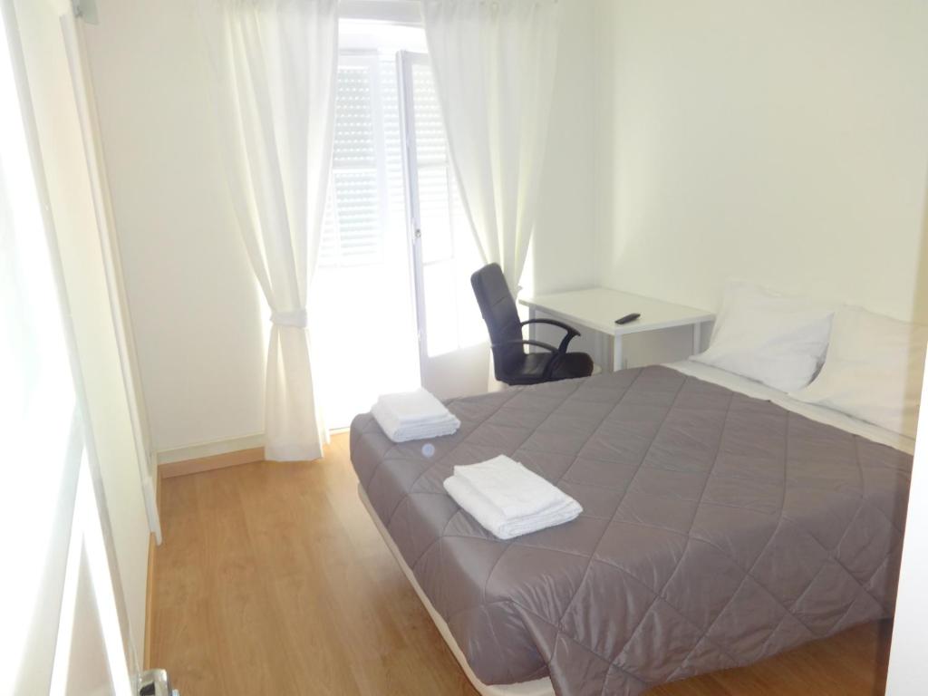 Un dormitorio con una cama y una silla y una ventana. en Residence Metro-Alameda, en Lisboa