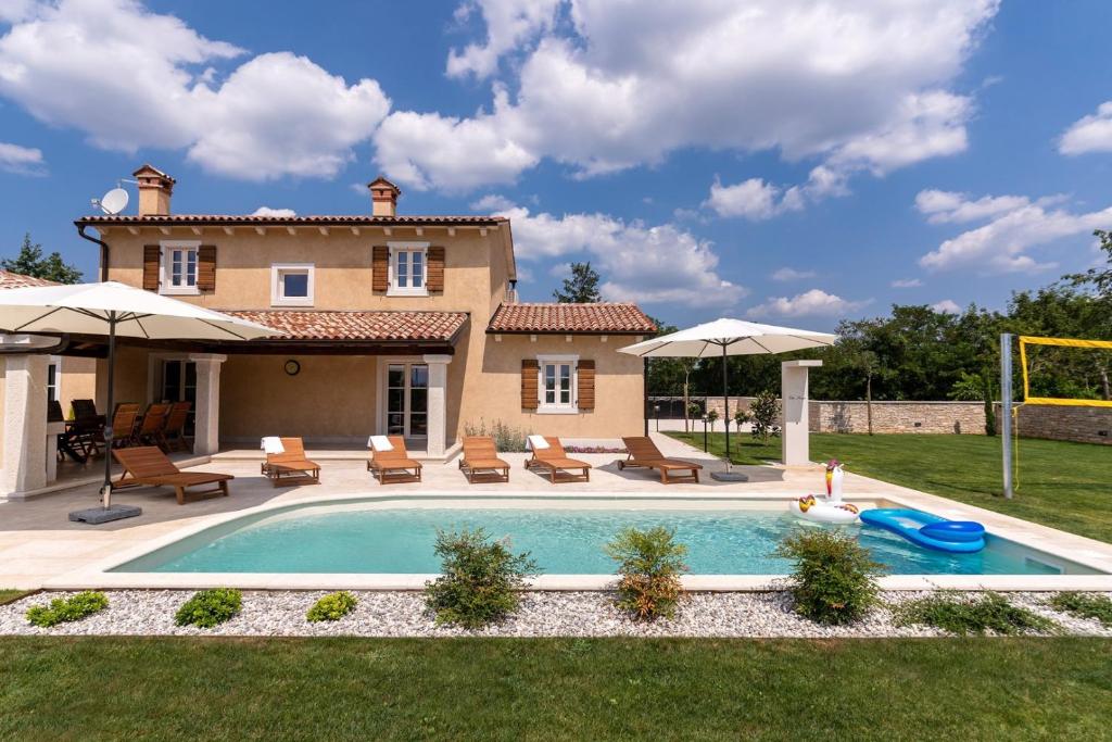 een zwembad voor een huis met stoelen en parasols bij Villa Lucija in Katun Gračanski