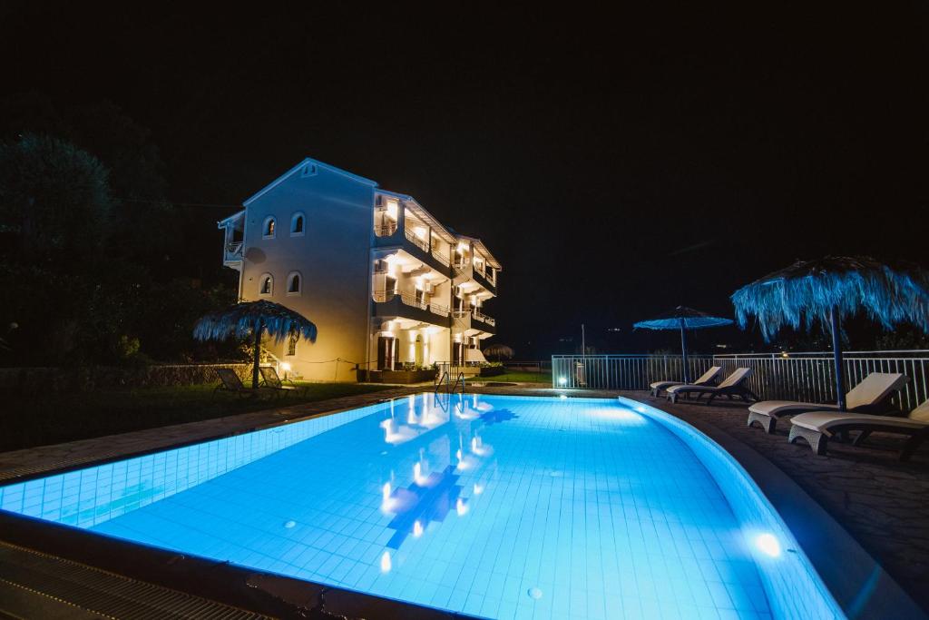una piscina di fronte a un edificio di notte di Giorgos apartments a Dassia