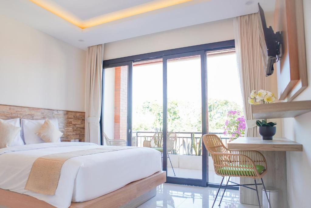 a bedroom with a large bed and a balcony at Cansa Seminyak in Seminyak