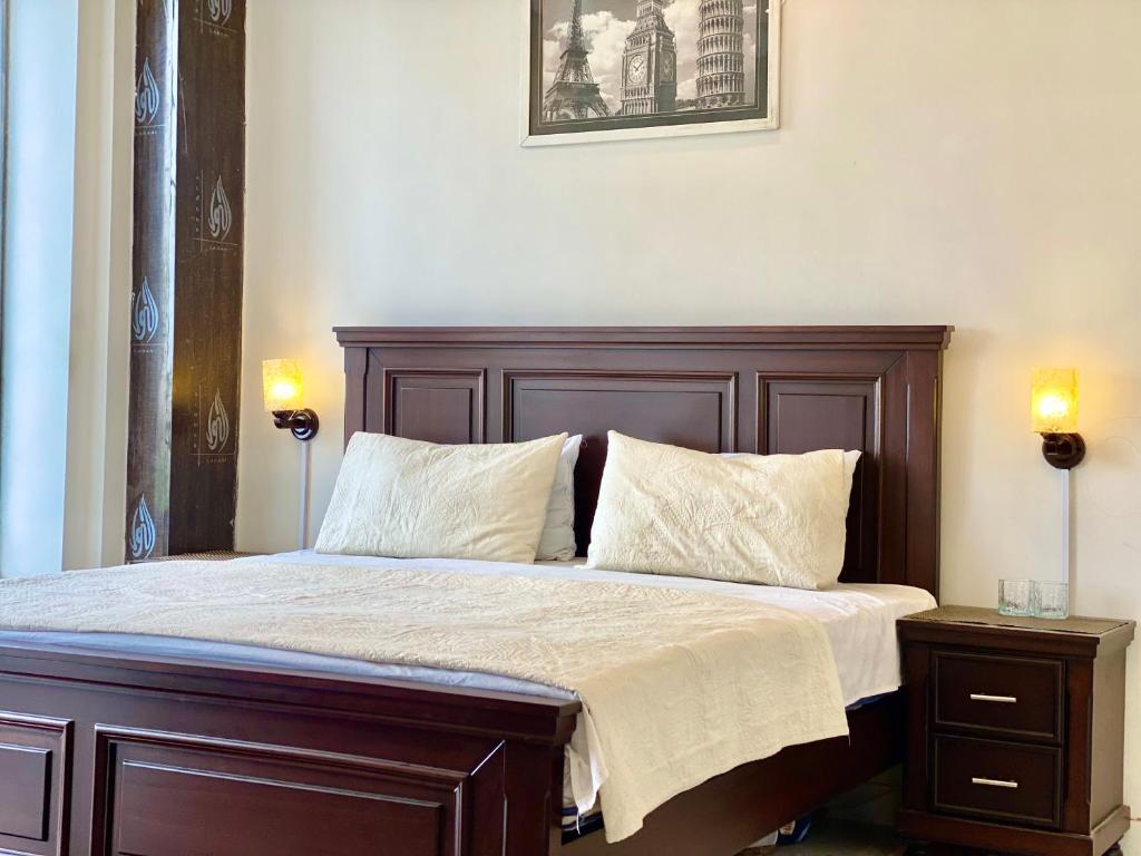 a bed with a wooden headboard and two lamps at 1-Bed Elegant Condo at Eiffel TW in Rāmkot